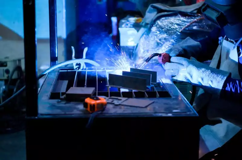 Soudeur en plein travail avec un poste MIG inverter, étincelles et arc électrique visibles