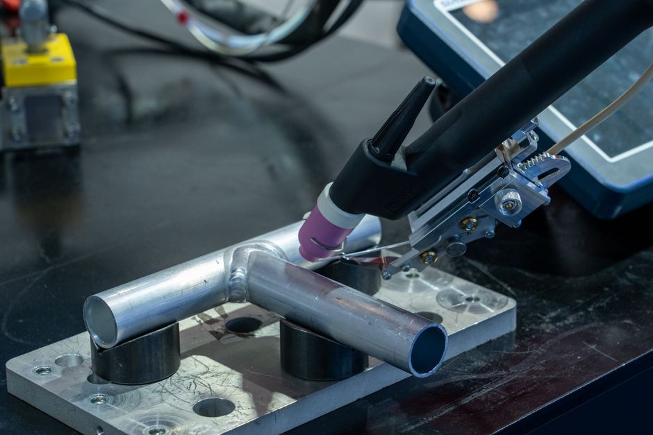 Torche TIG à buse céramique au-dessus d’un assemblage en T de tubes aluminium