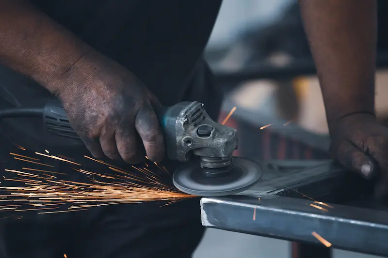 Travailleur en train de découper du métal avec une meuleuse à disque